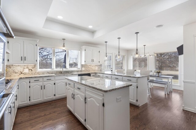 kitchen with a peninsula, a kitchen island, a wealth of natural light, and a sink