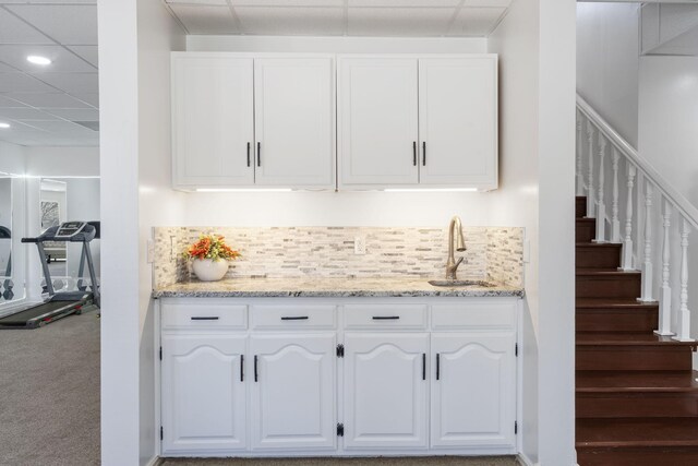 bar featuring decorative backsplash, a sink, and a drop ceiling