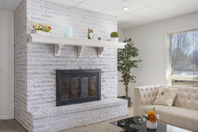 living room featuring carpet floors, a drop ceiling, and a fireplace