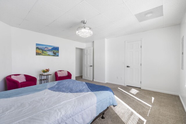 carpeted bedroom featuring a paneled ceiling, baseboards, and a notable chandelier