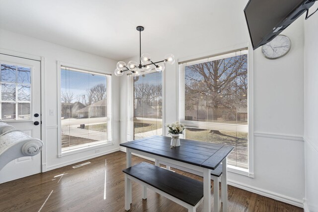dining space featuring wood finished floors, visible vents, baseboards, and a notable chandelier