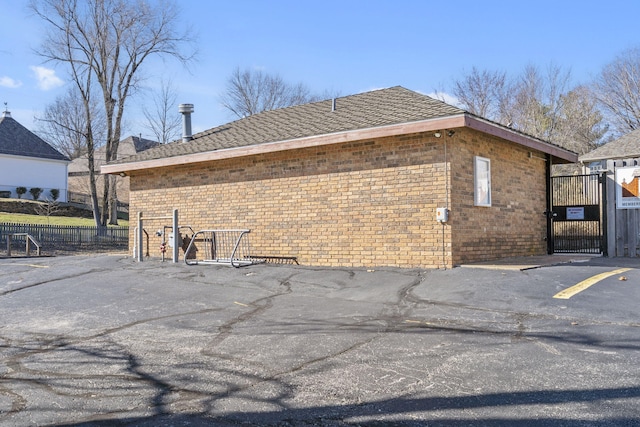 view of side of home featuring fence, brick siding, and a gate