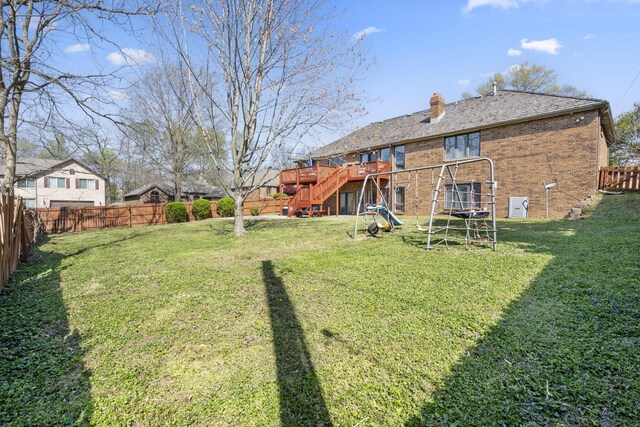 rear view of house featuring a fenced backyard, a chimney, brick siding, stairs, and a deck