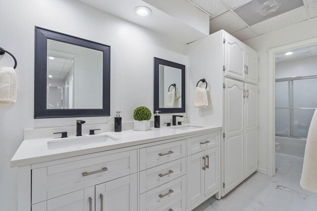 bathroom with recessed lighting, double vanity, marble finish floor, and a sink