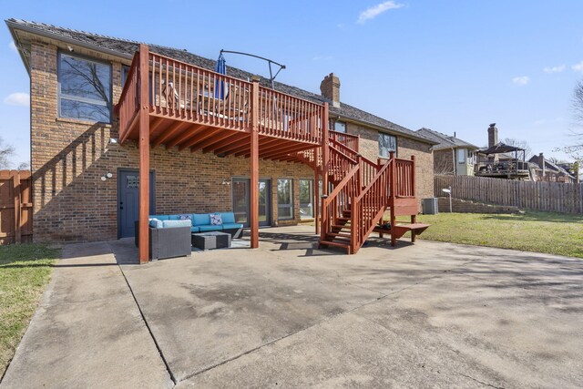 rear view of house featuring an outdoor living space, a wooden deck, brick siding, and a patio