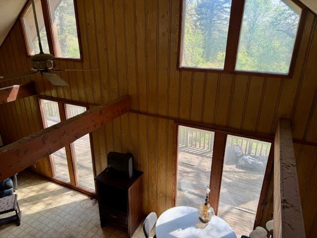 interior space with ceiling fan, a healthy amount of sunlight, and wooden walls