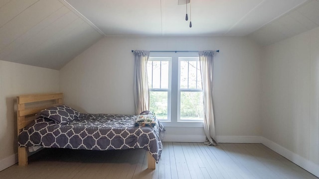 bedroom featuring lofted ceiling, hardwood / wood-style flooring, and baseboards