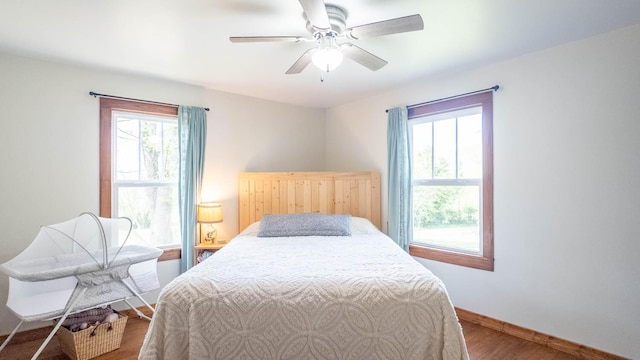 bedroom with a ceiling fan, wood finished floors, and baseboards