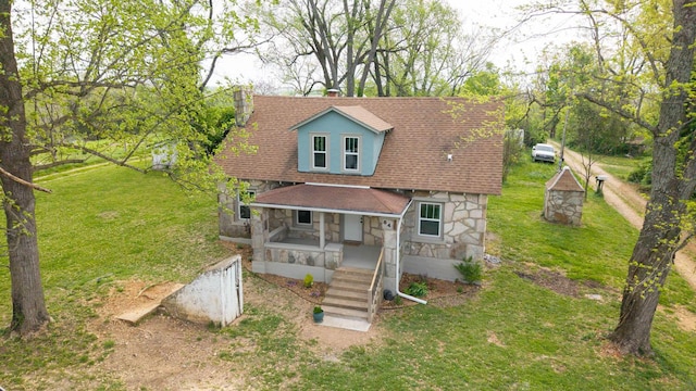 view of front of property with a front lawn, stone siding, and covered porch