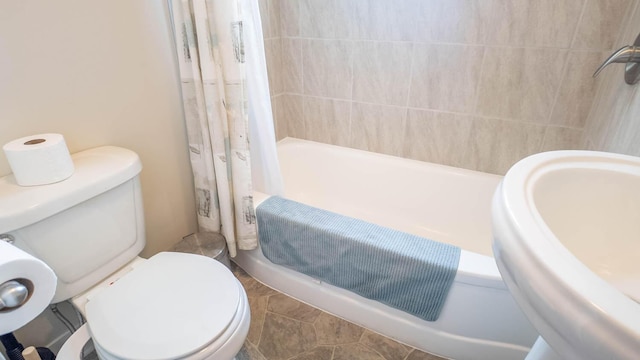 bathroom featuring shower / bath combo, toilet, and a sink