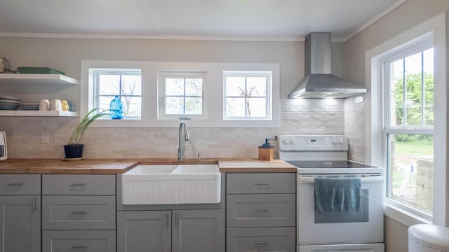 kitchen featuring decorative backsplash, wood counters, white range with electric stovetop, a sink, and wall chimney exhaust hood