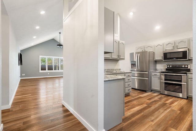 kitchen featuring wood finished floors, lofted ceiling, recessed lighting, gray cabinetry, and stainless steel appliances