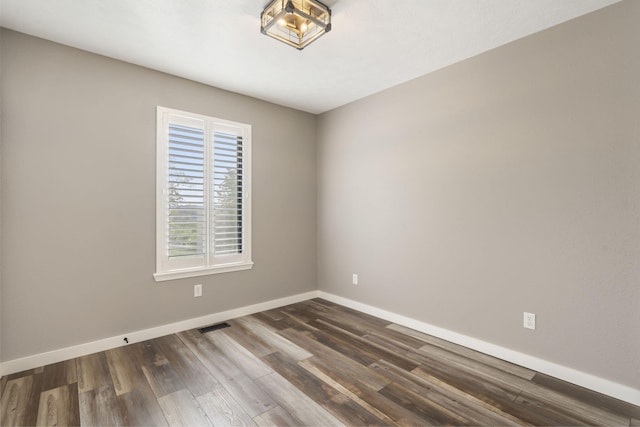 spare room with dark wood-style flooring, baseboards, and visible vents