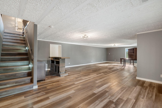 below grade area featuring stairs, crown molding, baseboards, and wood finished floors