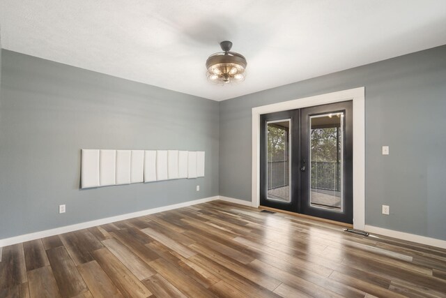 empty room featuring french doors, baseboards, wood finished floors, and visible vents