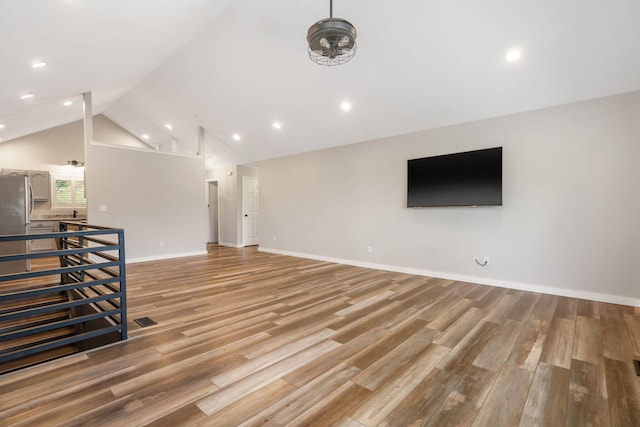 unfurnished living room featuring visible vents, baseboards, light wood-type flooring, recessed lighting, and vaulted ceiling