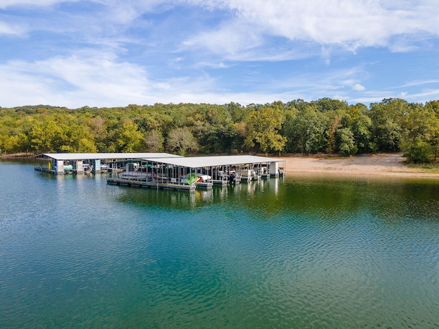 dock area with a water view, boat lift, and a wooded view