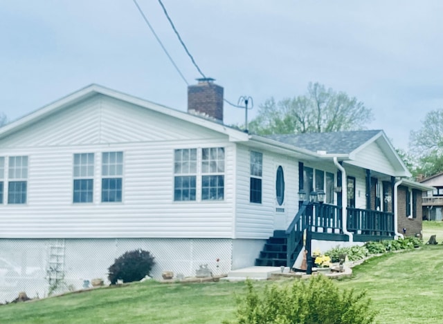 view of front facade featuring a front yard, covered porch, and a chimney