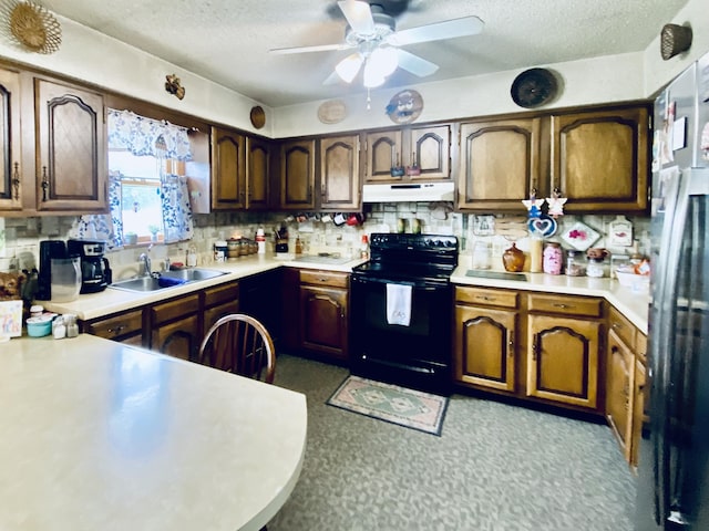 kitchen featuring a sink, under cabinet range hood, black electric range oven, light countertops, and a textured ceiling