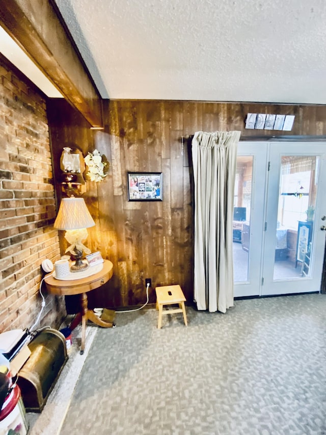 sitting room with wooden walls, a textured ceiling, and carpet