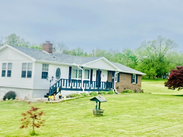 view of front of property with a chimney, brick siding, a porch, and a front lawn