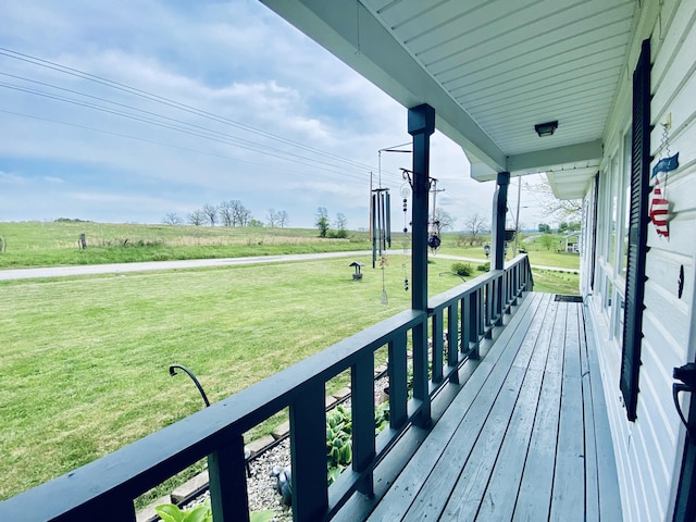 wooden terrace featuring a porch, a yard, and a rural view