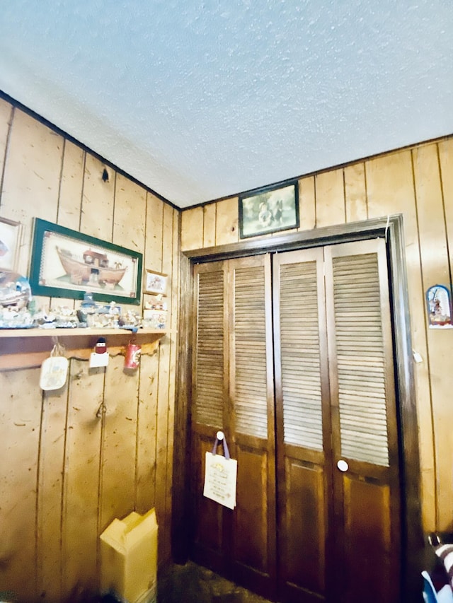 mudroom with wooden walls and a textured ceiling