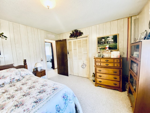 carpeted bedroom featuring wood walls, a textured ceiling, and a closet