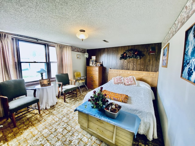 bedroom featuring wood walls, a textured ceiling, visible vents, and carpet