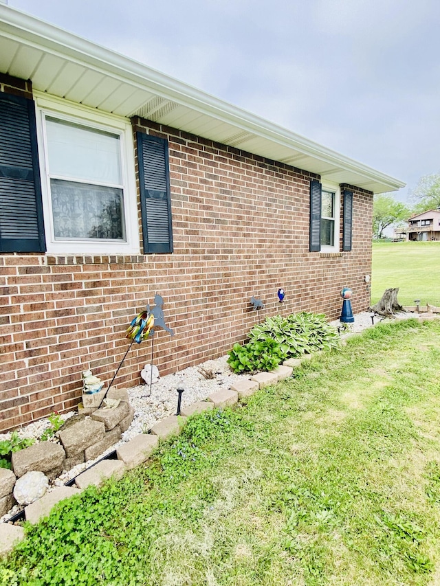 view of property exterior featuring brick siding and a yard