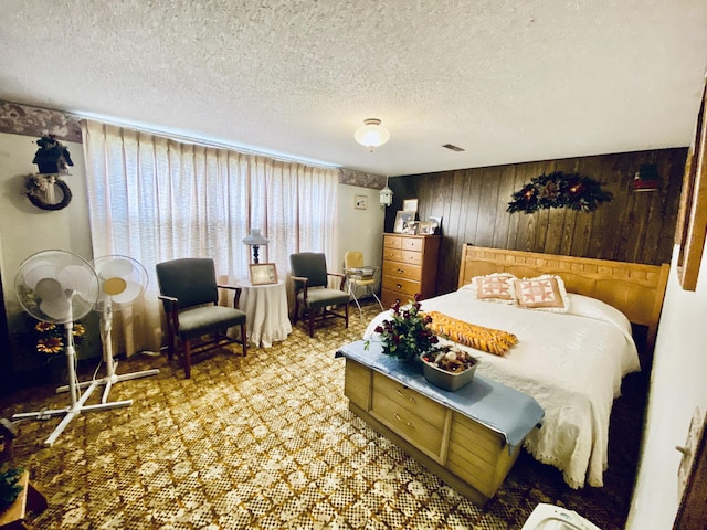 bedroom with visible vents, wooden walls, and a textured ceiling