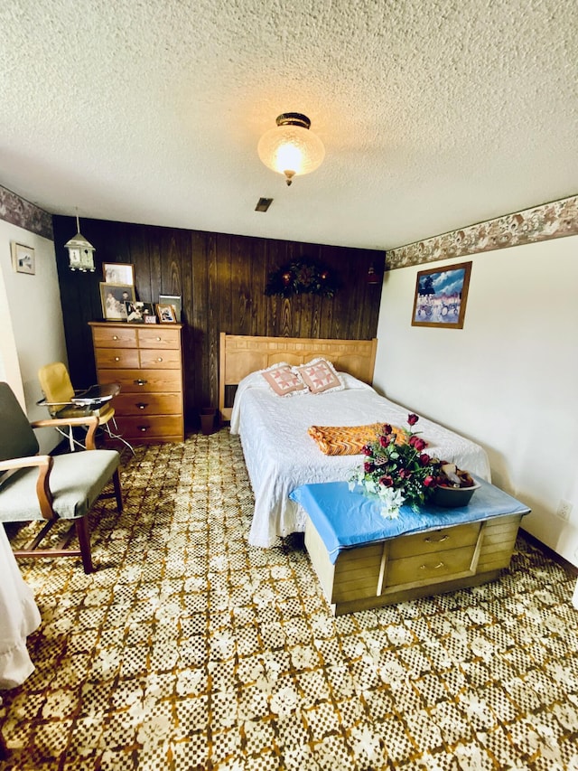 bedroom with a textured ceiling, wooden walls, and carpet flooring