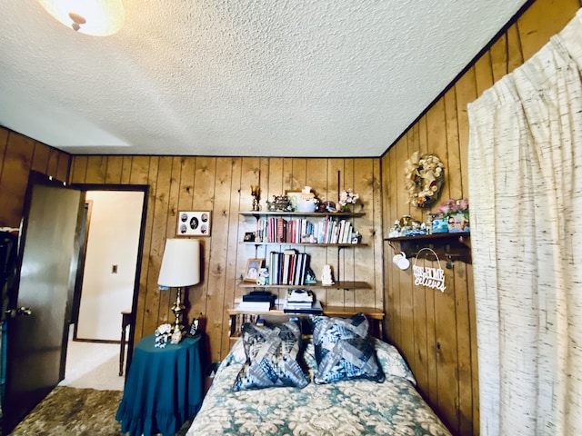 bedroom featuring wooden walls, a textured ceiling, and carpet flooring