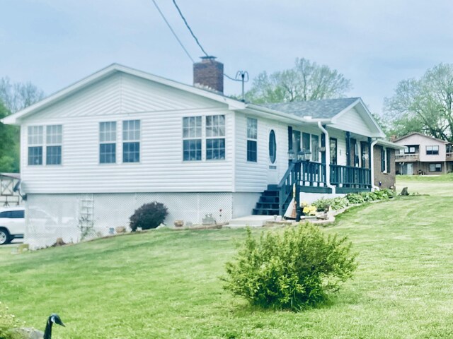 view of front of house featuring a porch, a chimney, and a front yard