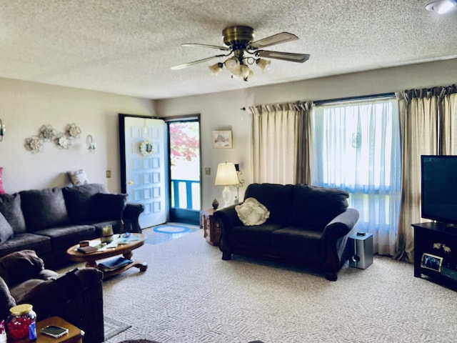 living room with a wealth of natural light, a ceiling fan, carpet flooring, and a textured ceiling