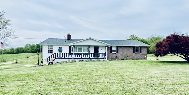 view of front of house featuring a front lawn, roof with shingles, brick siding, and a chimney