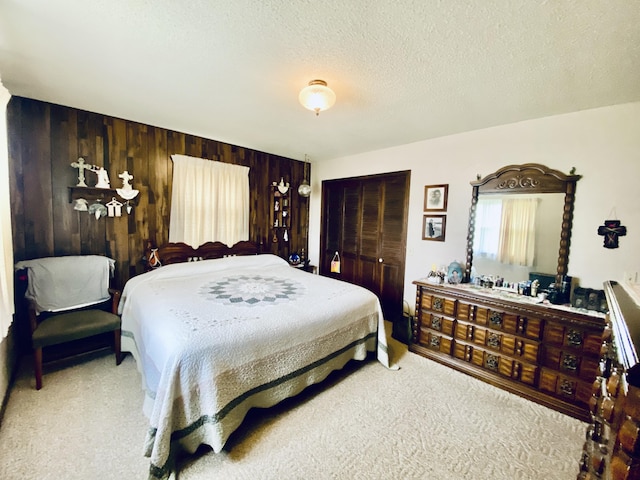 carpeted bedroom with a textured ceiling, wooden walls, and a closet
