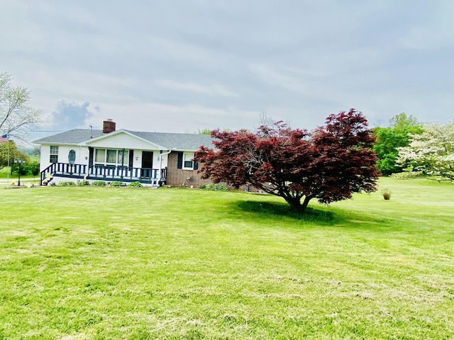view of front of property featuring a chimney, brick siding, and a front lawn