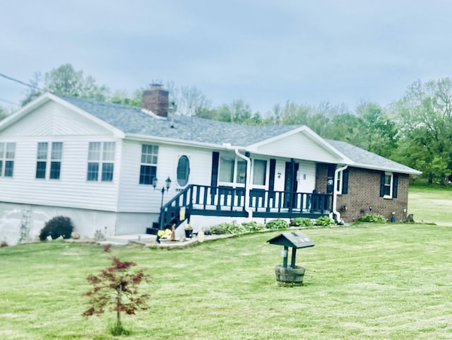 ranch-style home featuring a front yard, brick siding, covered porch, and a chimney