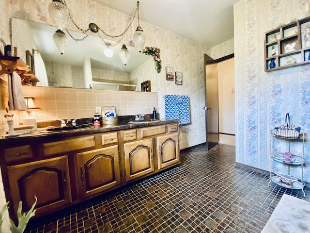 full bath featuring double vanity, a sink, wallpapered walls, and tasteful backsplash