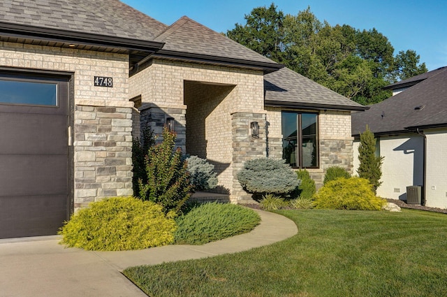 4748 Forest Trails Dr, Springfield, MO 65809 - property entrance with a shingled roof, a lawn, stone siding, brick siding, and a garage