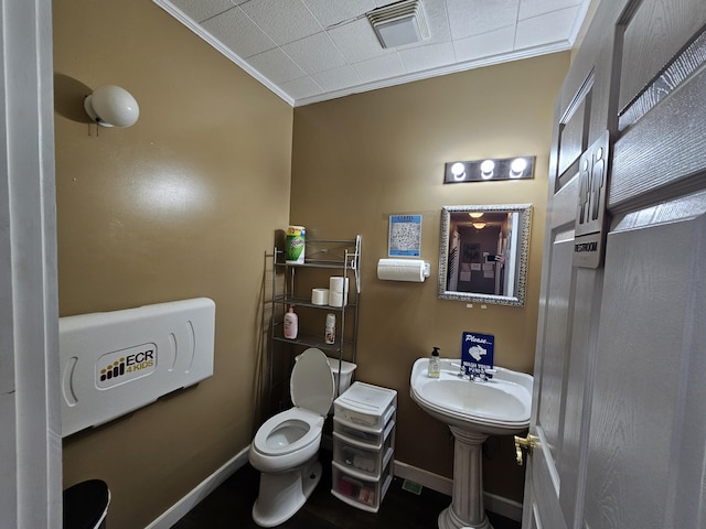 half bath with ornamental molding, toilet, visible vents, and baseboards