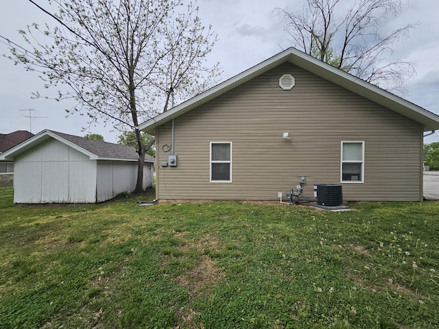 back of house featuring an outbuilding, a lawn, and central AC