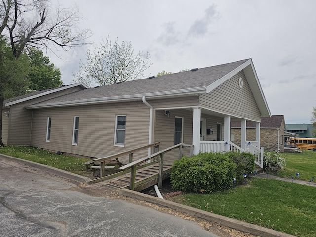 view of front of home featuring roof with shingles, a porch, and a front lawn