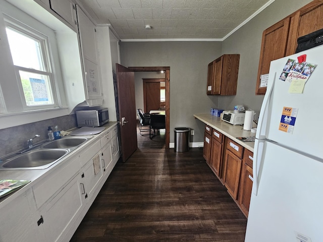 kitchen with stainless steel microwave, a sink, freestanding refrigerator, dark wood-style flooring, and ornamental molding