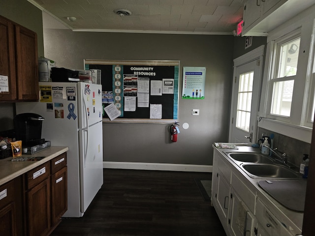 kitchen with freestanding refrigerator, light countertops, ornamental molding, a sink, and dark wood-style floors