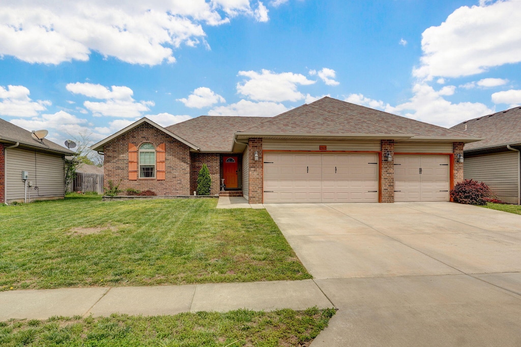 ranch-style home with brick siding, driveway, roof with shingles, a front yard, and an attached garage