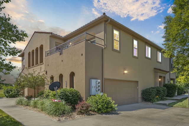 140 S Tuscany Dr Unit C, Hollister, MO 65672 - view of home's exterior featuring stucco siding, concrete driveway, a balcony, and an attached garage