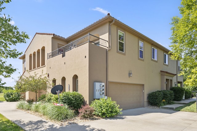 140 S Tuscany Dr Unit C, Hollister, MO 65672 - view of home's exterior with concrete driveway, a garage, stucco siding, and a balcony