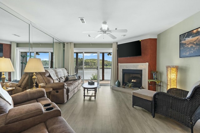 living room featuring a fireplace, wood finished floors, visible vents, and a ceiling fan